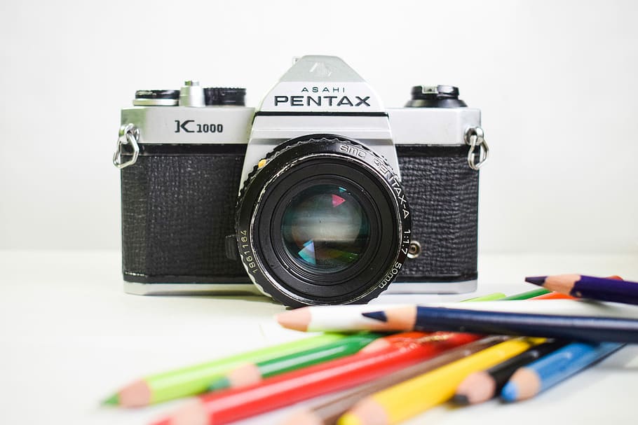 selective focus photography of Pentax K1000 camera, assorted-color pens near gray Pentax DSLR camera, HD wallpaper