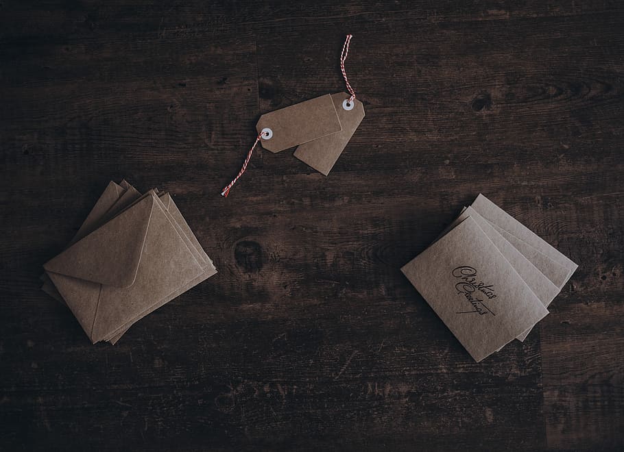 Christmas cards and tags, envelopes and two product tags on brown surface HD wallpaper