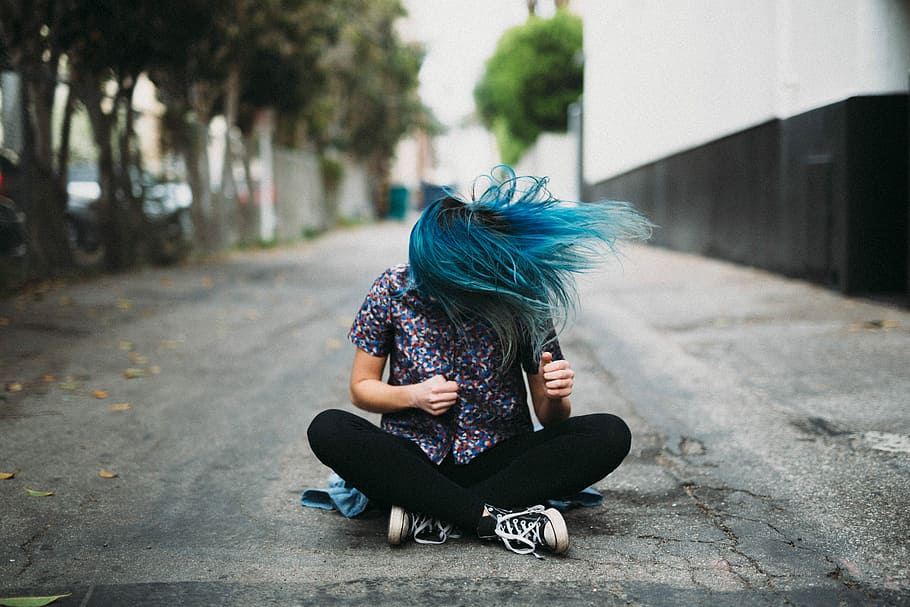 woman sitting on ground beside buildings, man wearing black denim jeans sitting beside the buildign HD wallpaper