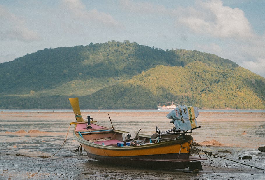 orange boat on seashore during daytime across mountain, brown boat in seashore HD wallpaper