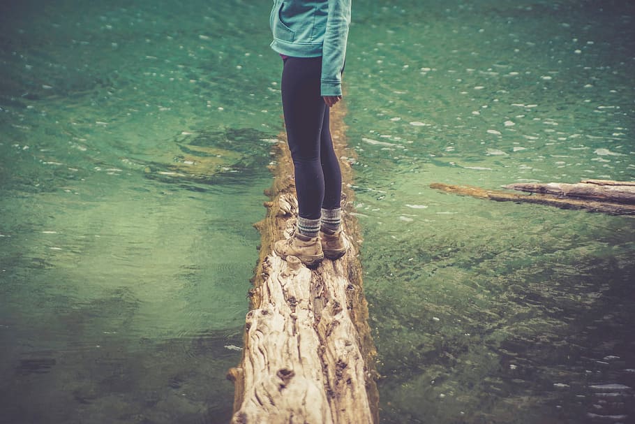 woman in black leggings standing on withered tree log on river HD wallpaper