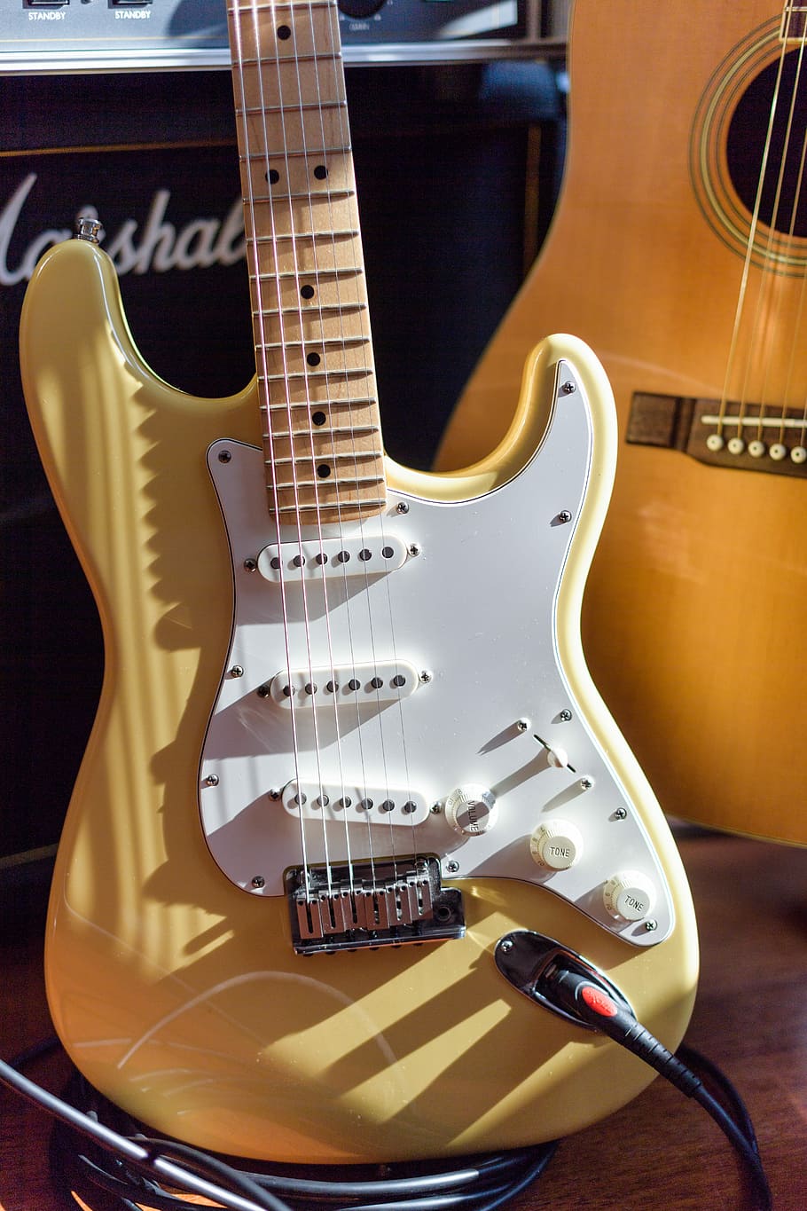 brown and white electric guitar, yellow and white electric guitar