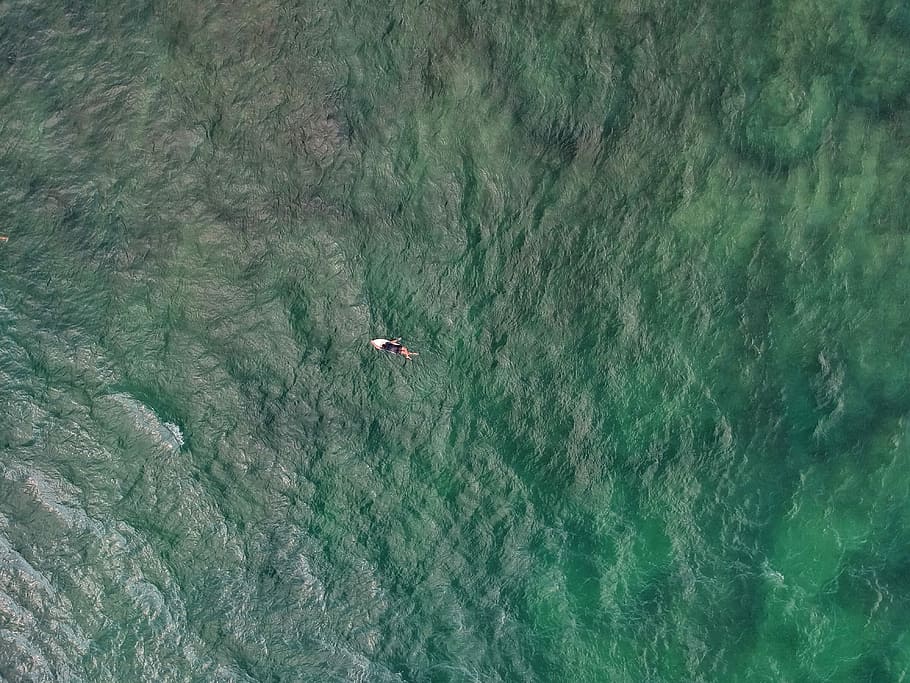 top-view photo of person on top of surfboard on body of water, aerial photography of body of water