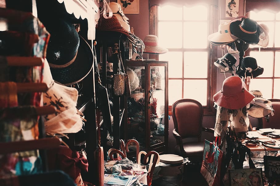 assorted-brand product lot near window, photography of assorted hats and brown wooden curio cabinet inside room during daytime HD wallpaper