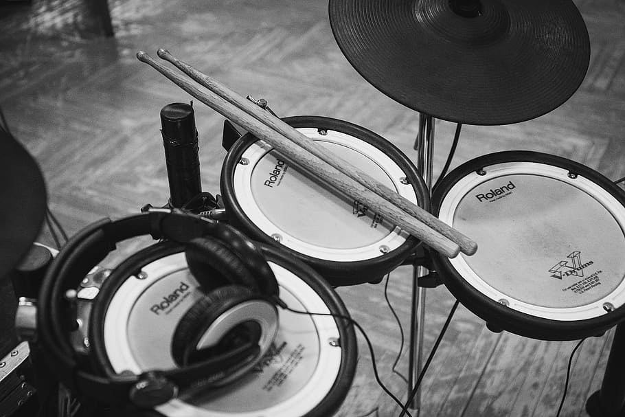 grayscale photo of drum stick and headphones on drum pad, electric