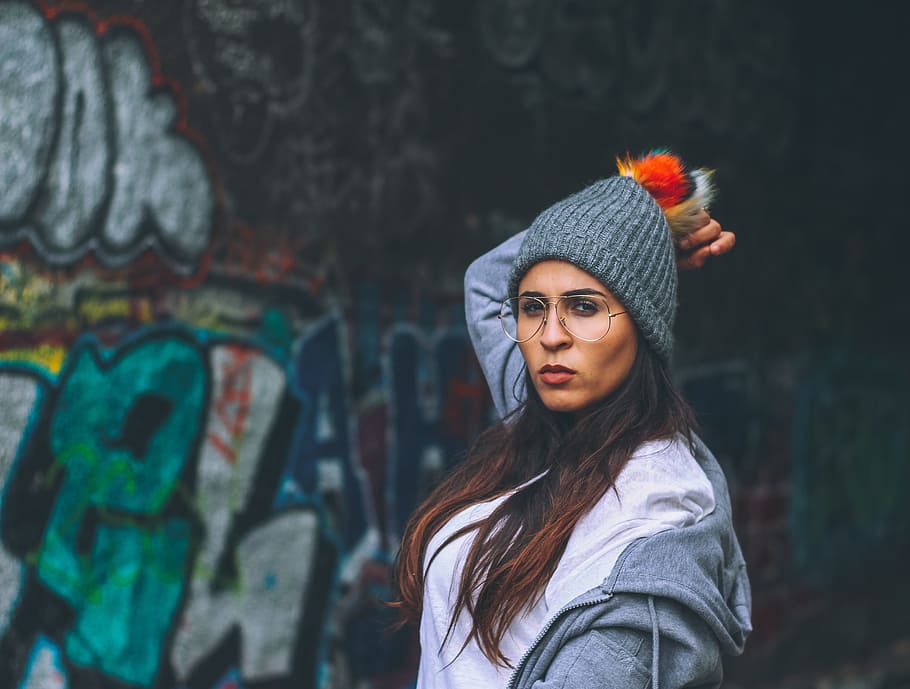 woman wearing gray top raising her hand, woman wearing gray bobble hat and eyeglasses HD wallpaper