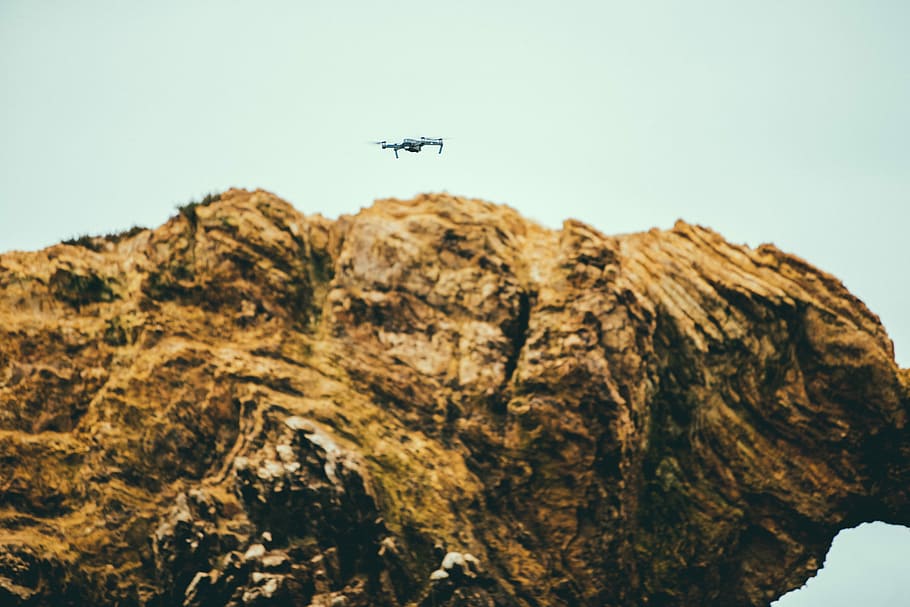 drone on brown concrete stone, white drone flying around boulder HD wallpaper
