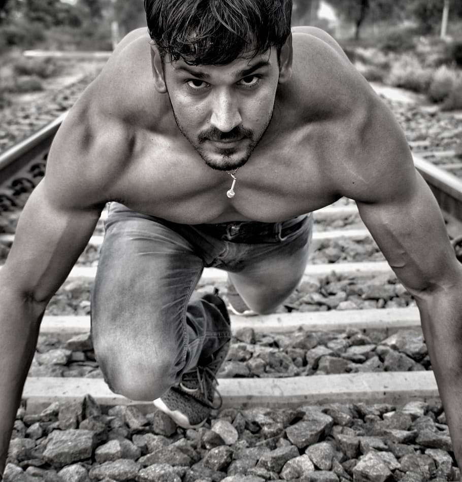man wearing jeans standing on train tracks, chest, arm, thigh