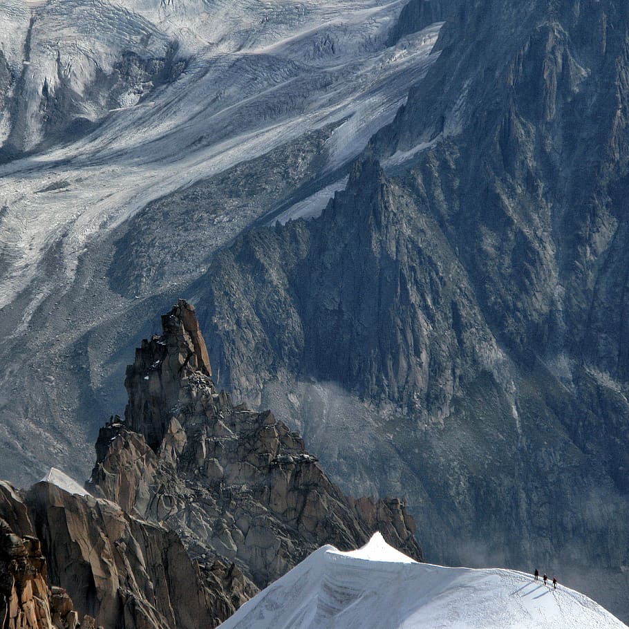 bird's eye view of rock mountain peak, trekkers on top of snowy mountain peak