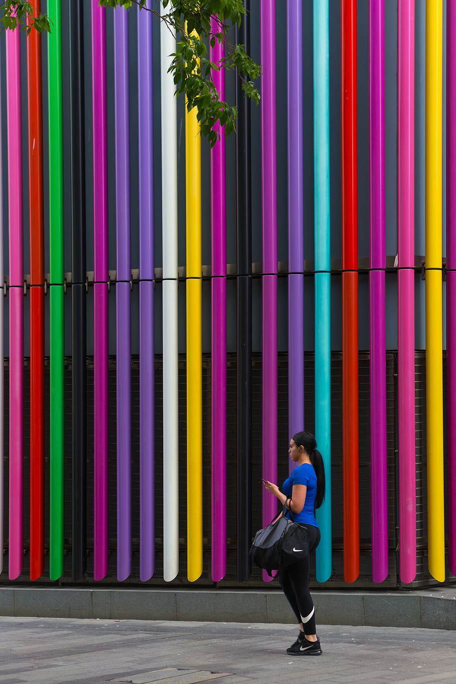 woman standing near the multicolored building wall at daytime, woman standing on multicolored wall HD wallpaper