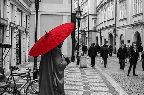 selective color photography of man holding red umbrella while standing during daytime HD wallpaper