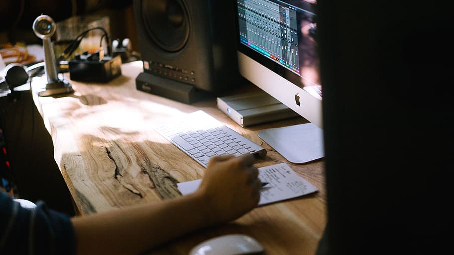 person using silver iMac, Apple Magic Keyboard, and Magic Mouse set, person sitting near beige wood stamp desk HD wallpaper