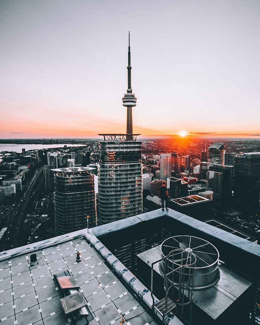 person standing on top of building in front of CN tower during sunset, man standing on building HD wallpaper