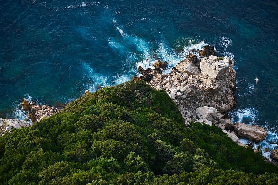 Rocky cliff from above, aerial photography of mountain surrounded by body of water