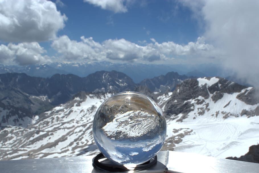 water globe on gray surface in front of mountain peak, zugspitze
