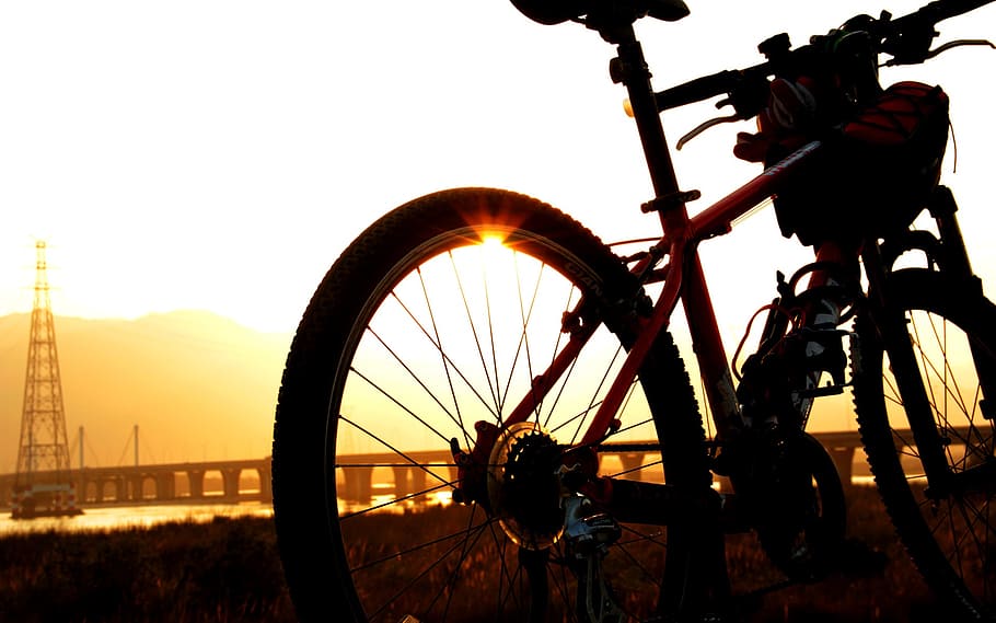 red hardtail mountain bike parked on grass field during golden hour HD wallpaper