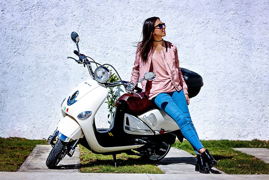 woman wearing pink blazer sitting on white and black automatic scooter during daytime