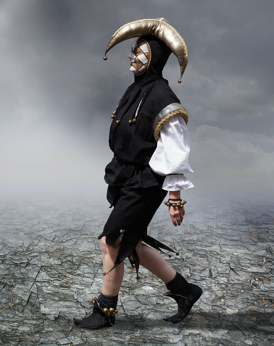 person wearing black, white, and gold jester suit, harlequin