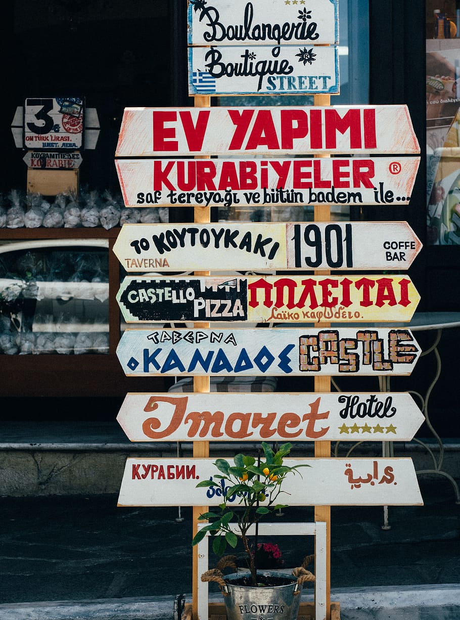 beige, red, and brown signages on beige stand at daytime, assorted wooden signs near store HD wallpaper