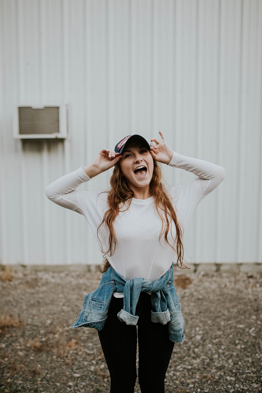 woman wearing black cap standing outside the house while laughing, photo of woman holding curve-brimmed cap HD wallpaper