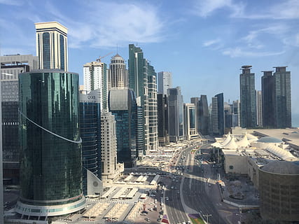 vehicles on concrete road between city buildings during daytime HD wallpaper
