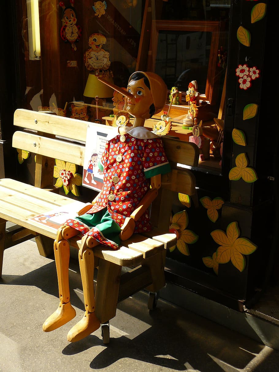 Pinocchio sitting on brown bench, holzfigur, figure, carving