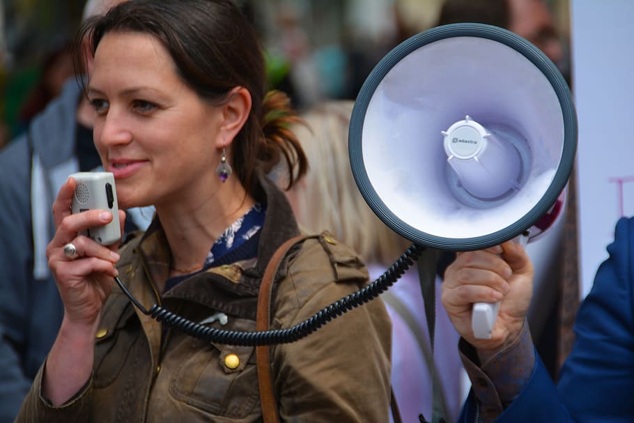 woman in brown jacket holding megaphone during daytime, loud speaker
