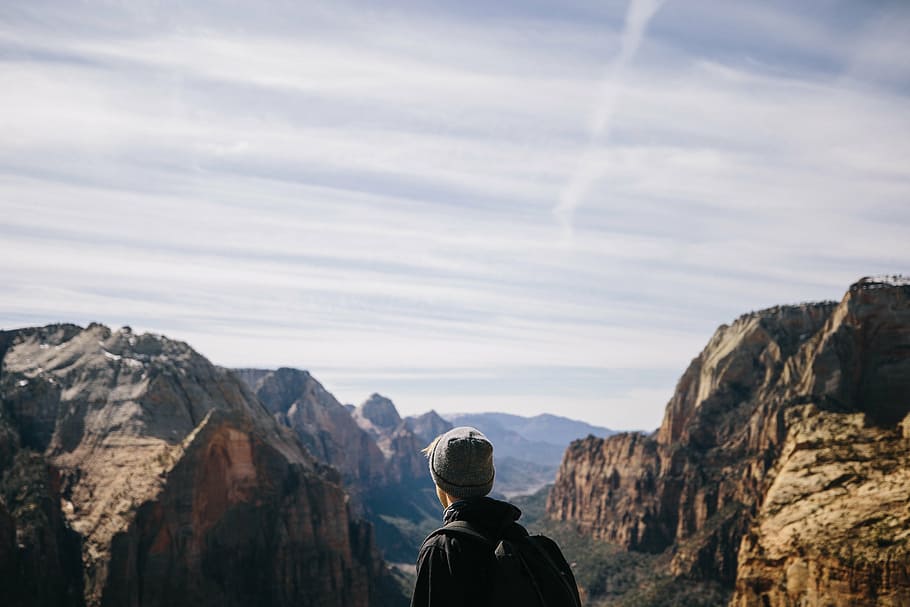 man wearing backpack facing rock formations, mountain, highland HD wallpaper