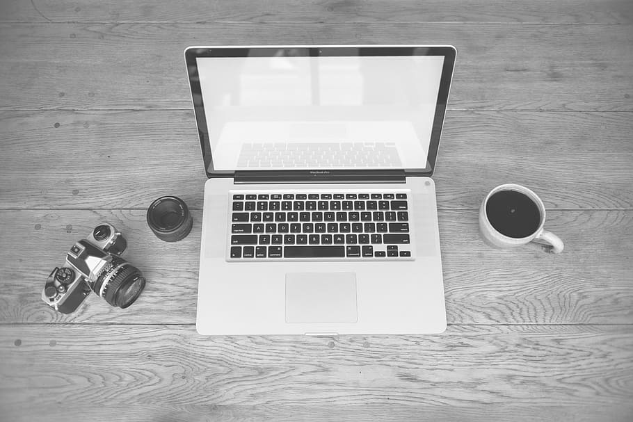 MacBook Pro beside mug teacup filled with black liquid substance and MILC camera HD wallpaper