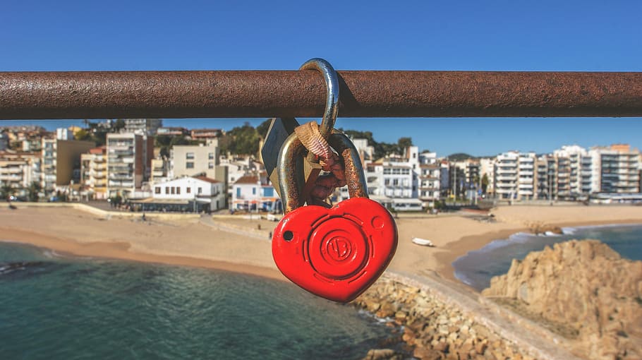 heart padlock hanging on brown pipe, red and grey heart padlock on brown bar