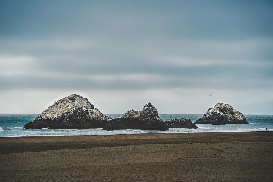 mountains on body of water, islands on water near seashore under gray sky HD wallpaper