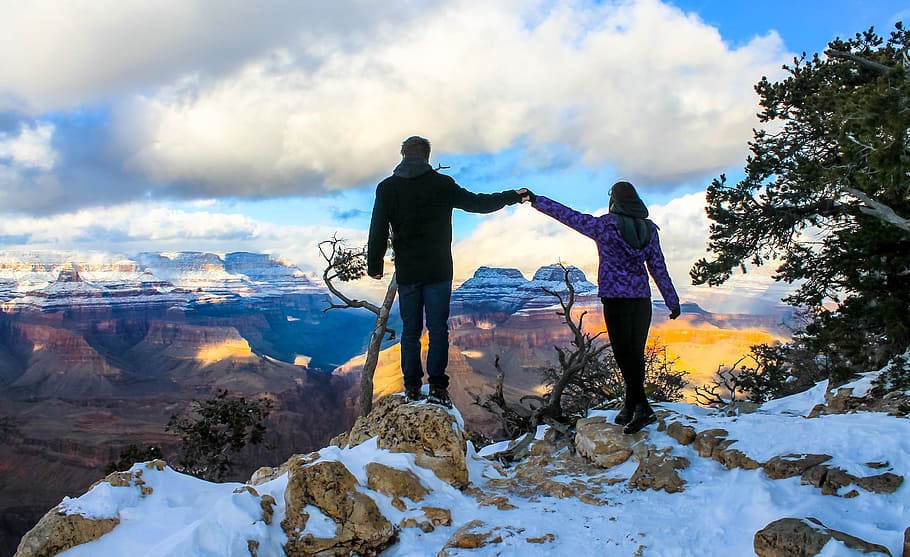 man and woman holding hands standing on top of cliff, Grand Canyon