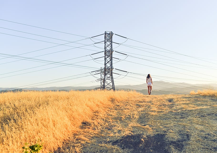 person standing on grass field near electricity post, power, utility