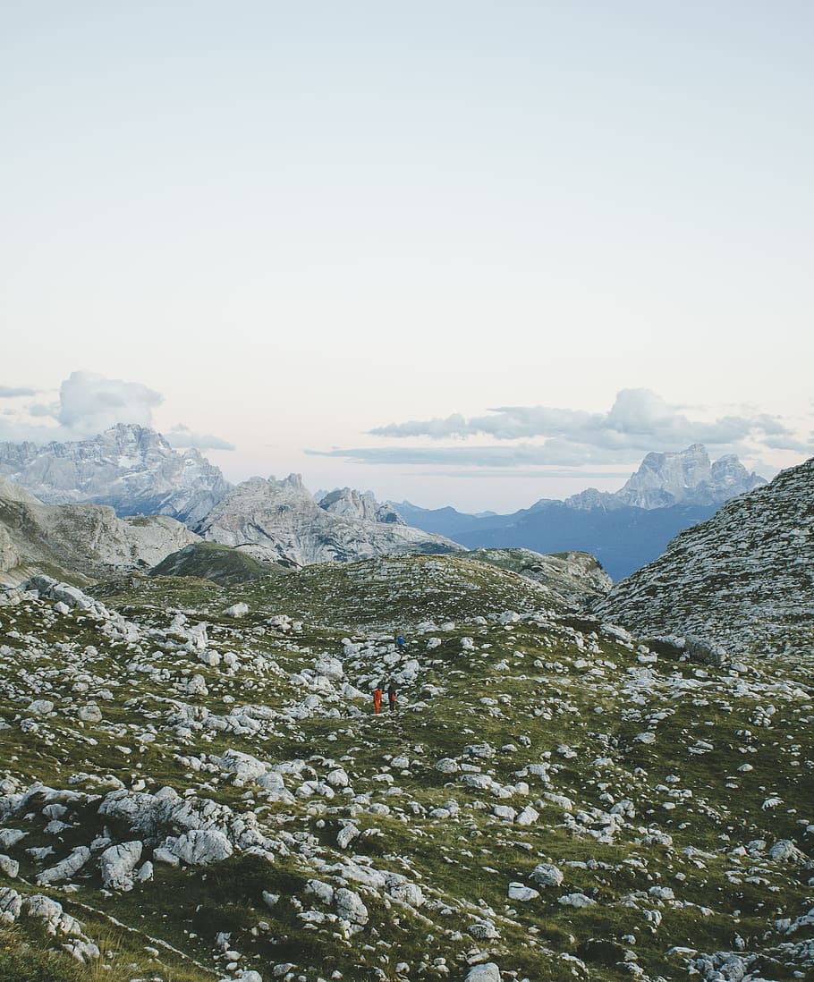 two people walking on hill under cloudy sky, green and gray mountain during daytime HD wallpaper
