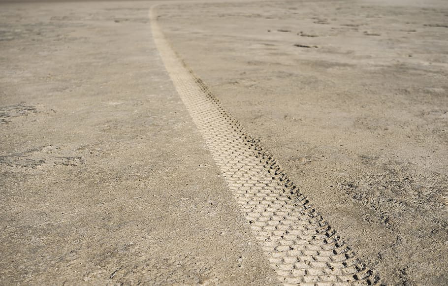 close-up photography of track tire print on ground, brown concrete floor