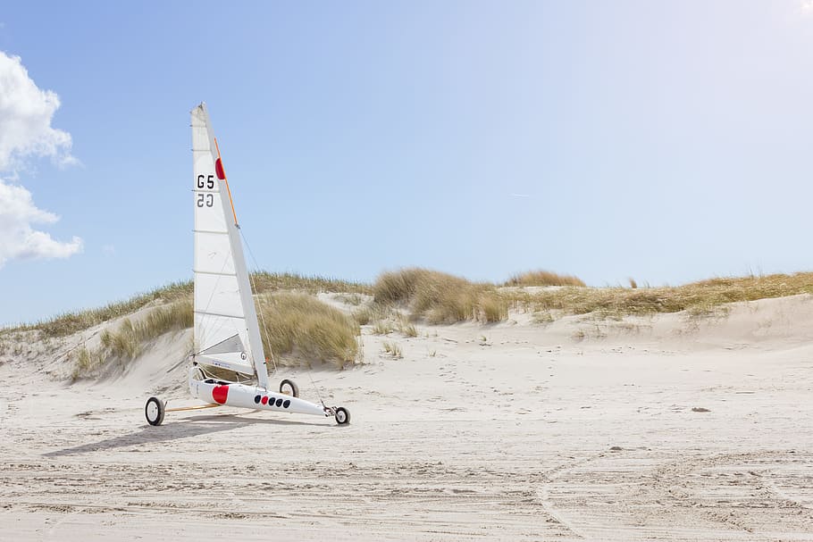 landscape photo of white sailboat with wheels on sand, white, red, and black 3-wheel sail ride-on HD wallpaper