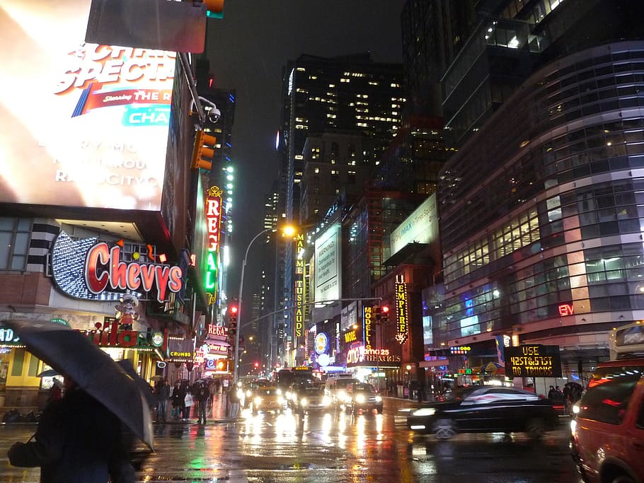 vehicles traveling on road between buildings during nighttime