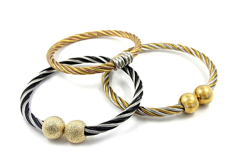 two gold-colored and one silver-colored bracelets on white surface HD wallpaper