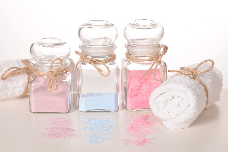 white towel beside three clear glass bottles with powders on brown surface
