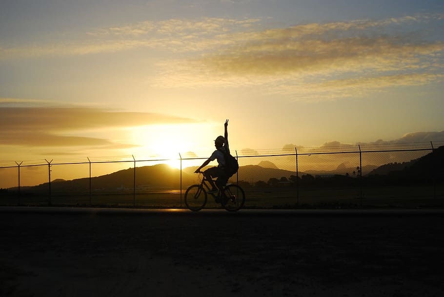 silhouette of woman riding a bike with view of sunset, cyclist