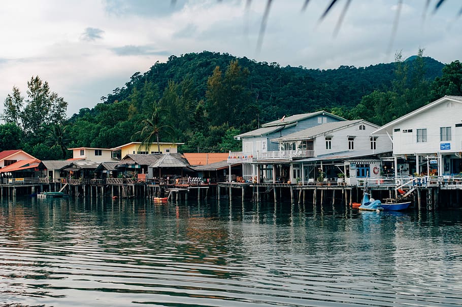 white painted house near body of water, white and brown houses above water near trees during daytime