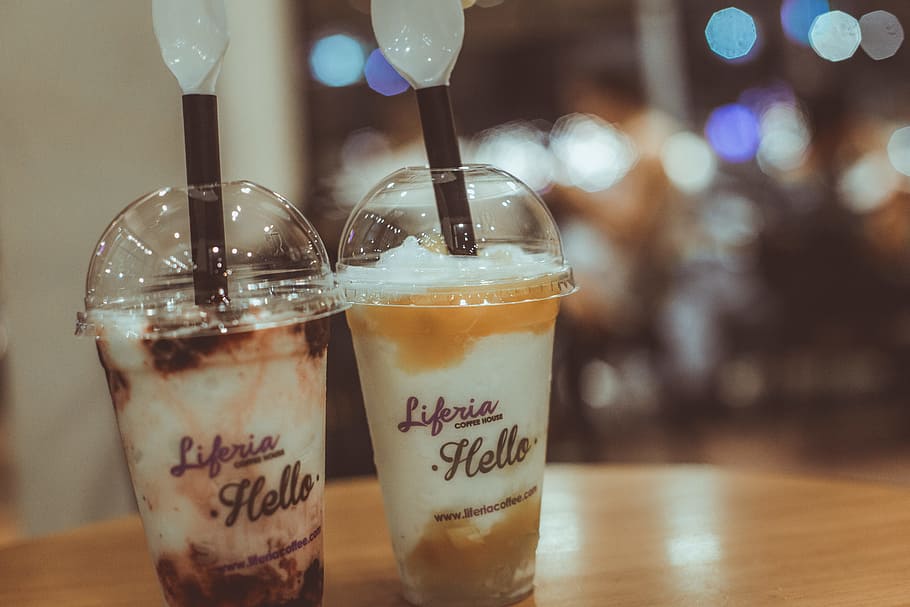 Two Liferia Hello Coffee Drinks on Brown Wooden Table, bokeh