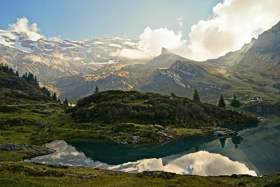calm body of water surrounded by mountains during daytime, lake surrounded by mountains