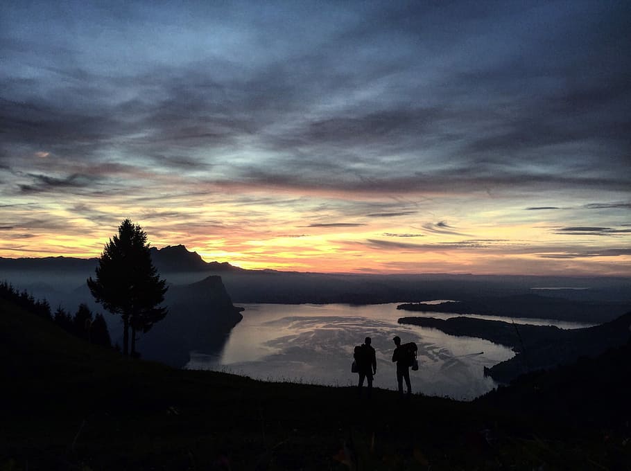 two person walking down on the mountain, silhouette of two person standing on cliff HD wallpaper