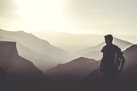 man standing on top of the mountain during daytime, man carrying black Adidas backpack HD wallpaper