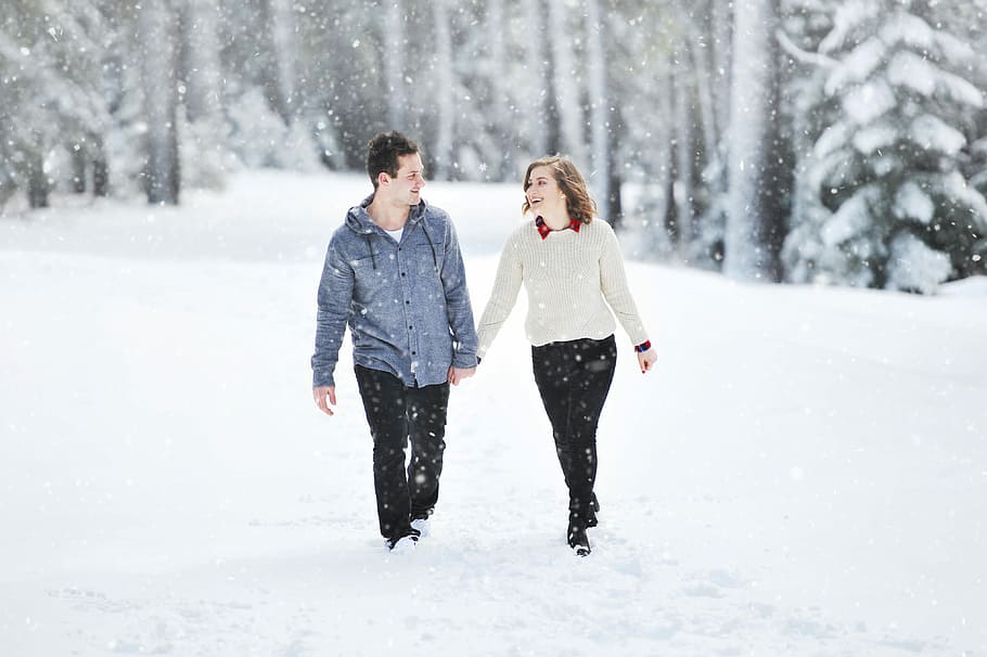 couple walking on snow near trees during daytime, shallow focus photography of man and woman walking on snow, HD wallpaper