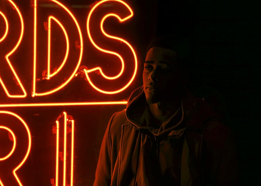 man standing in front of red neon signage during nighttime photo HD wallpaper