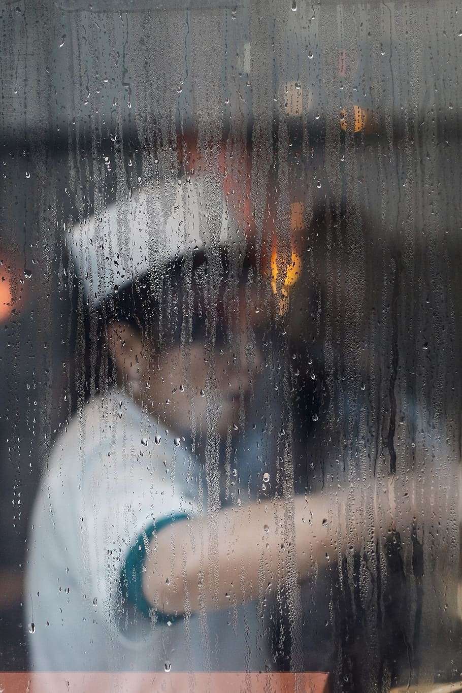 A cook at work seen through a rainy window, woman wearing white t-shirt and white hat inside establishment with glass wall HD wallpaper