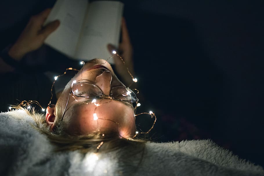 man reading book with string lights turned on, top-view of woman with eyeglasses reading book HD wallpaper