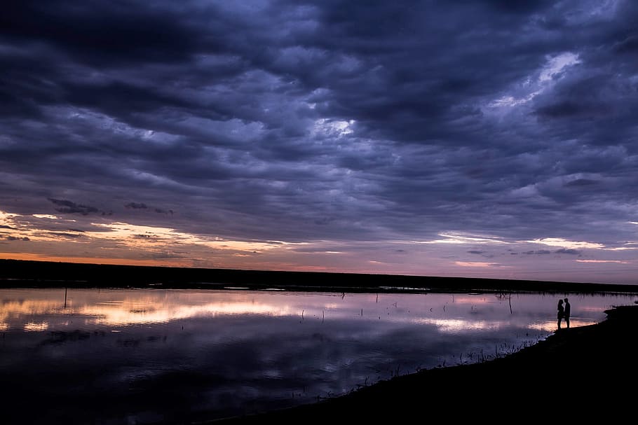 calm body of water under nimbus clouds at golden hour, sunset HD wallpaper